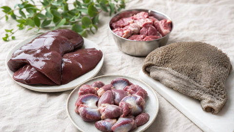 Raw offal for dogs including liver, giblets and tripe on a linen surface