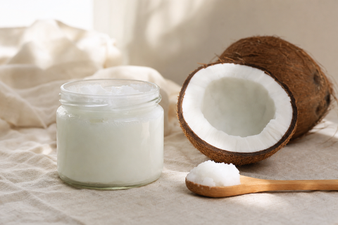A jar of coconut oil beside a calm dog, a supplement some raw feeders add in small amounts