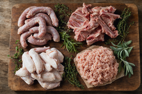 Different raw chicken cuts for dogs including necks, frames, and mince laid out on a board