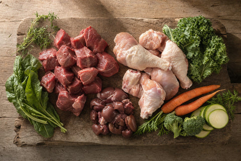 Raw beef, chicken and organ meat portions on a wooden board, ingredients for a German Shepherd raw diet