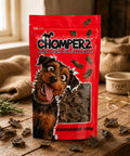 Chomperz Kangaroo Jerky 100g pack of air-dried Australian kangaroo dog treats on a wooden table with scattered jerky pieces